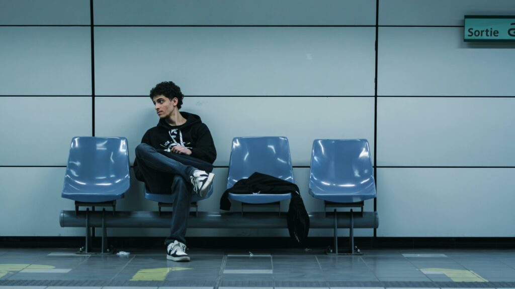 Jeune homme qui attend et regarde à sa droite sur un quai de métro
